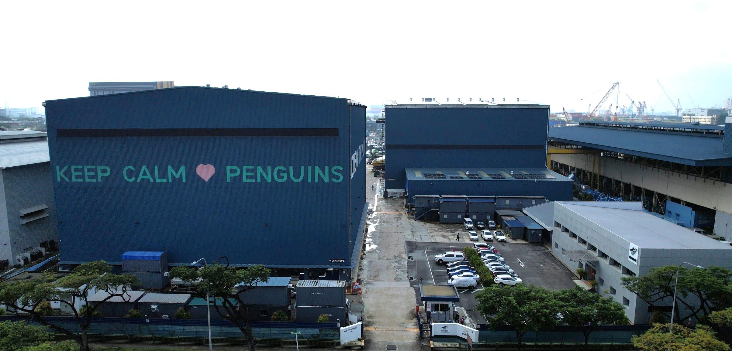 A dark blue building in the shipyard with large text "Keep Calm (heart) Penguins"