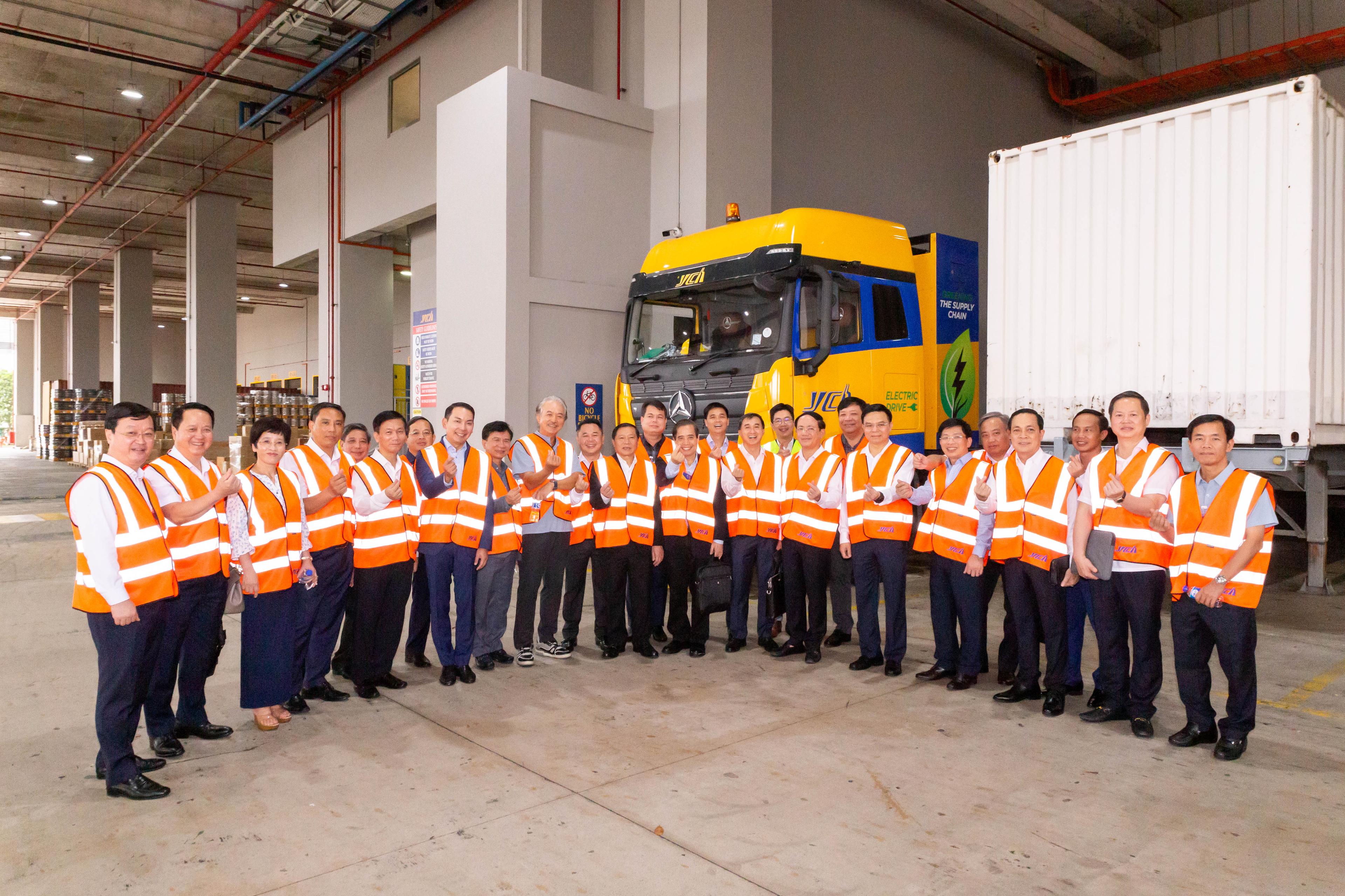 A group of people in orange vests posing for a photo in front of a truck.